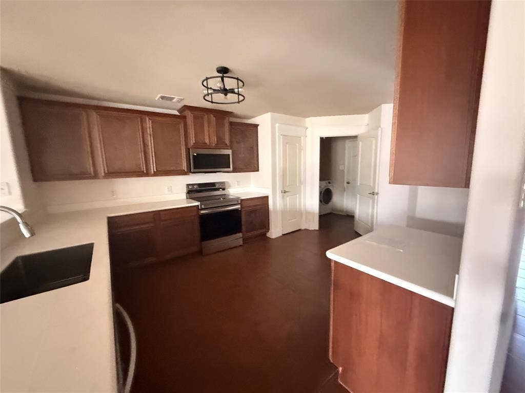 2004 Samantha Lane, Heartland, TX 75126 Kitchen featuring wood-finish flooring, white countertops, dark wood cabinetry, and stainless steel appliances including an oven range and microwave