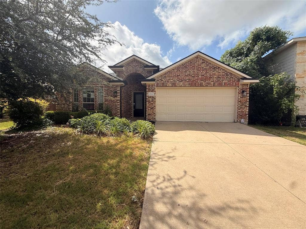 2004 Samantha Lane, Heartland, TX 75126 Brick exterior with a prominent arched entry, attached two-car garage, and a concrete driveway