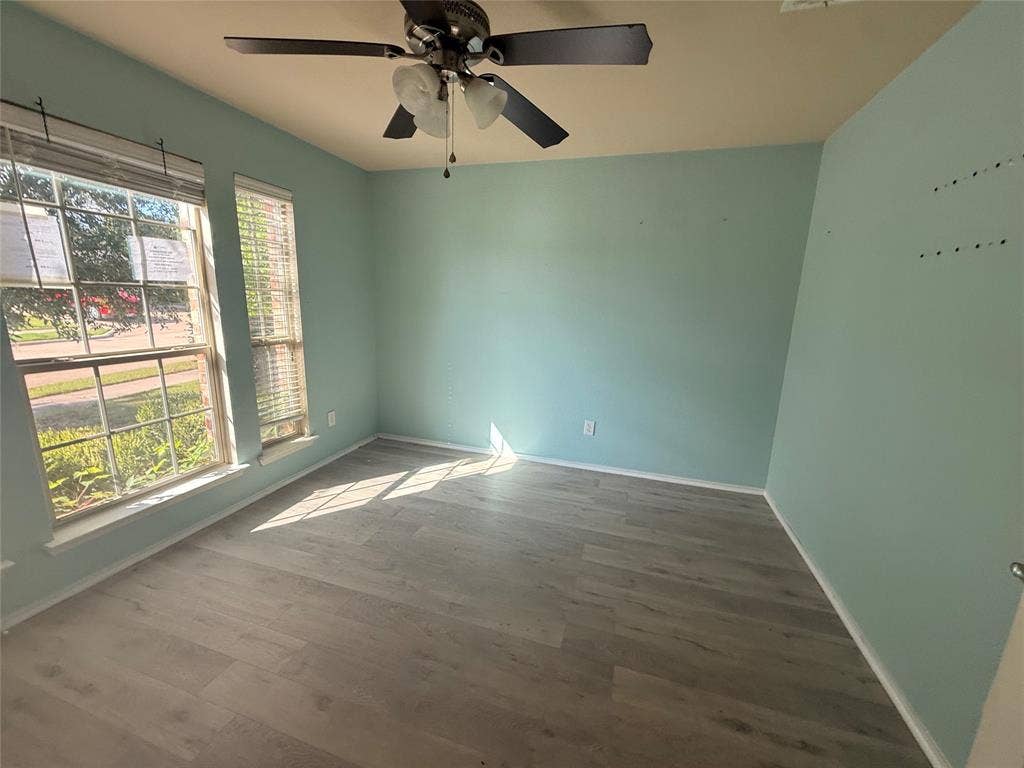 2004 Samantha Lane, Heartland, TX 75126 Room featuring wood-finish flooring, two large windows with blinds, a ceiling fan with integrated lighting, and light blue wall finishes