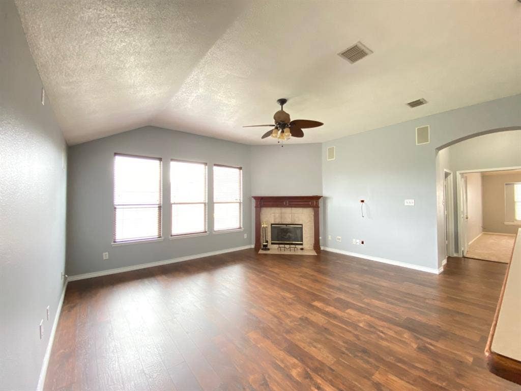 1328 Falcon Hollow, Cedar Hill, TX 75104 Spacious living area featuring a vaulted ceiling, wood-finish flooring, and a fireplace with a wood mantel