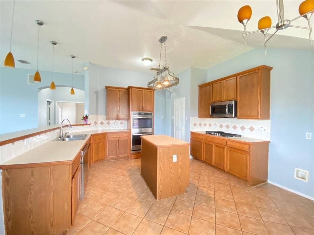 1328 Falcon Hollow, Cedar Hill, TX 75104 Spacious kitchen featuring warm wood cabinetry, light-toned countertops, and a central island