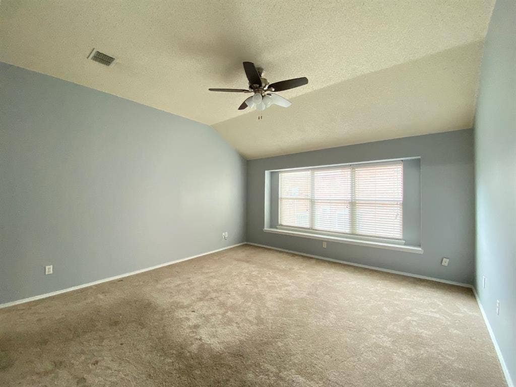 1328 Falcon Hollow, Cedar Hill, TX 75104 Vaulted ceiling room featuring a large window with blinds, light blue walls, and a ceiling fan with integrated lighting