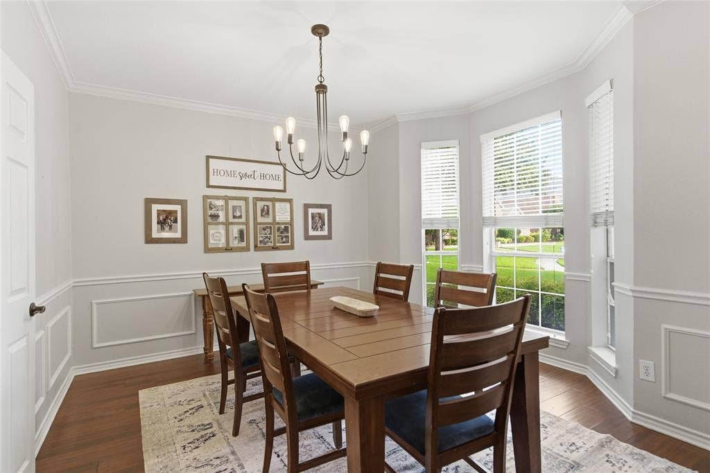 4112 Blackpool Drive, Plano, TX 75093 Dedicated dining area featuring a bay window with multiple panes, wood-finish flooring, wainscoting with decorative trim, crown molding, and a central chandelier