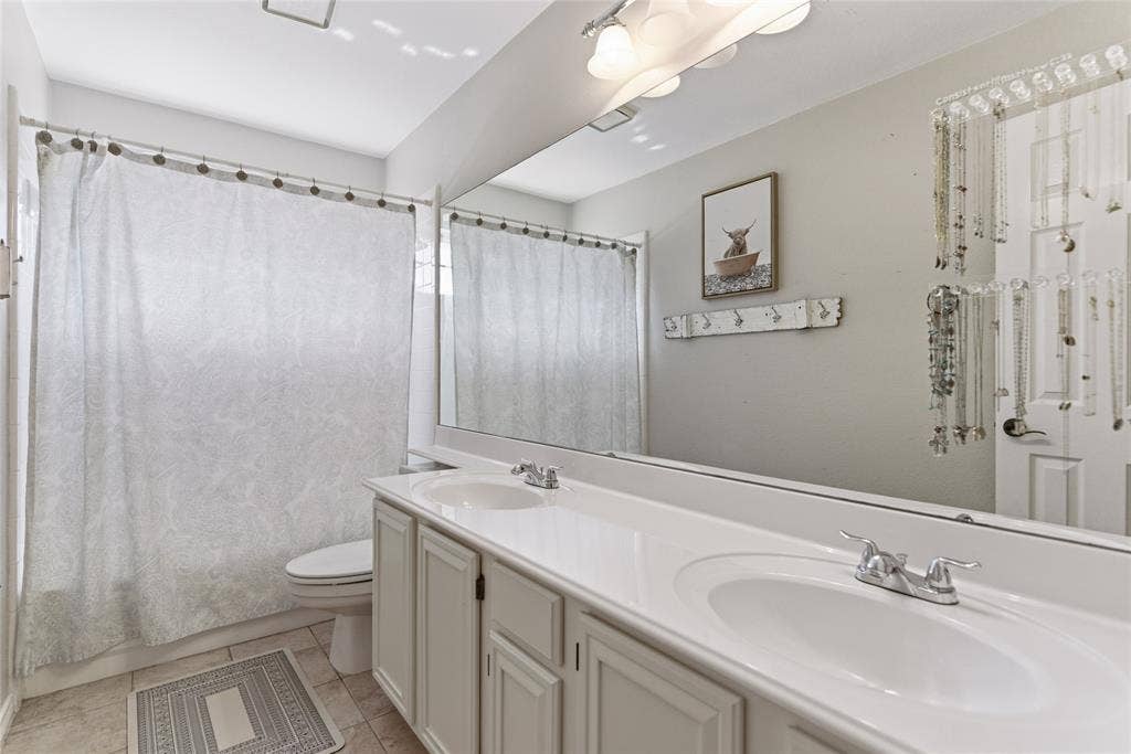 4112 Blackpool Drive, Plano, TX 75093 Bathroom featuring a dual vanity with integrated sinks, chrome faucets, and white cabinetry