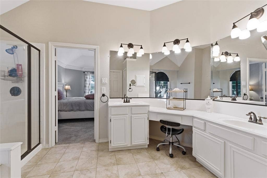 4112 Blackpool Drive, Plano, TX 75093 Bathroom featuring dual vanities, white cabinetry, extensive mirror coverage, a separate shower enclosure with a dark frame, and light-toned tile flooring