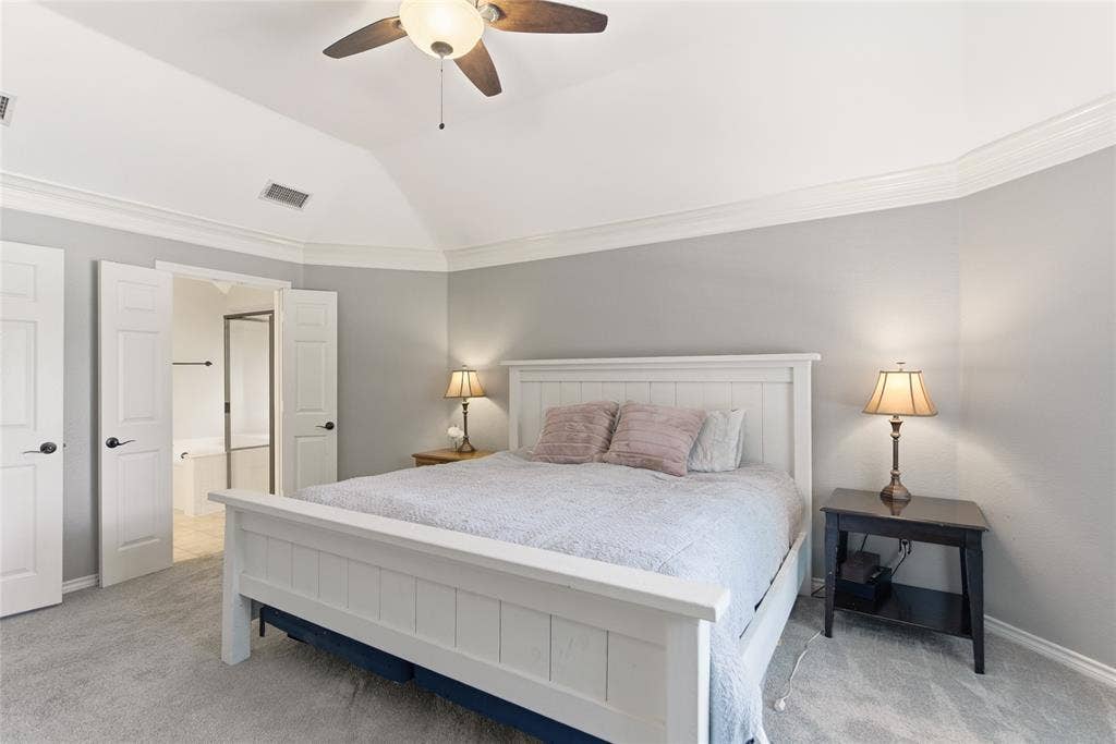 4112 Blackpool Drive, Plano, TX 75093 Vaulted ceiling with crown molding, ceiling fan, carpeted flooring, and double doors opening to a bathroom featuring a built-in tub and shower enclosure