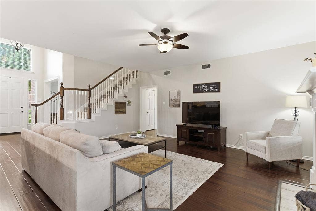 4112 Blackpool Drive, Plano, TX 75093 Living area featuring rich wood-finish flooring, a two-story entryway, and a prominent staircase with white balusters and dark wood handrails
