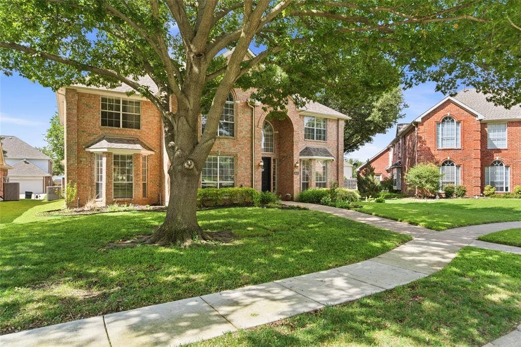 4112 Blackpool Drive, Plano, TX 75093 Brick exterior with multiple bay windows, an arched entry, and a mature tree providing shade