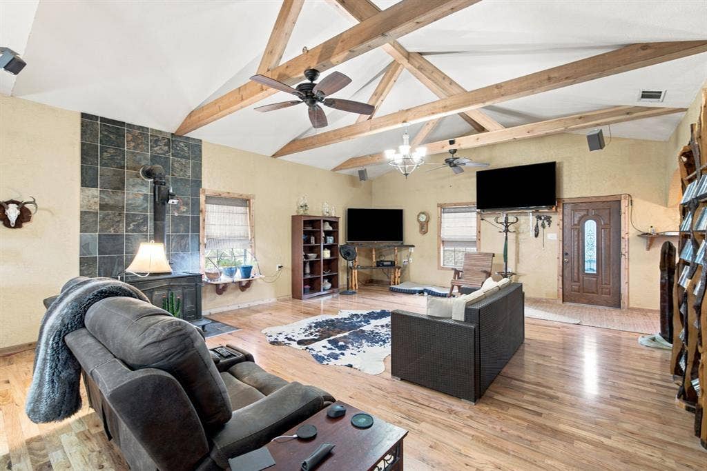 Beautiful wood beams are featured in the living area with rustic wood burning stove and hardwood floors. Second TV screen is for the security camera system that shows all around the property.  The system will stay with the home.