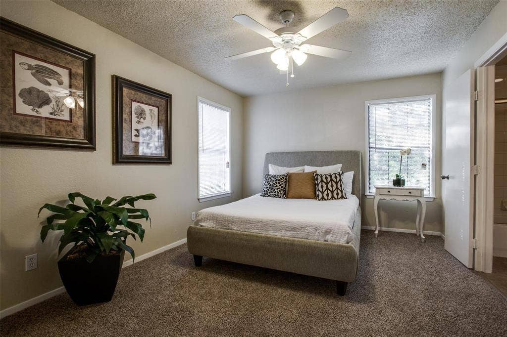 5322 Columbia Avenue, Dallas, TX 75214 Bright bedroom showcasing a bed, elegant dresser, ceiling fan and tall windows, creating a relaxing atmosphere.