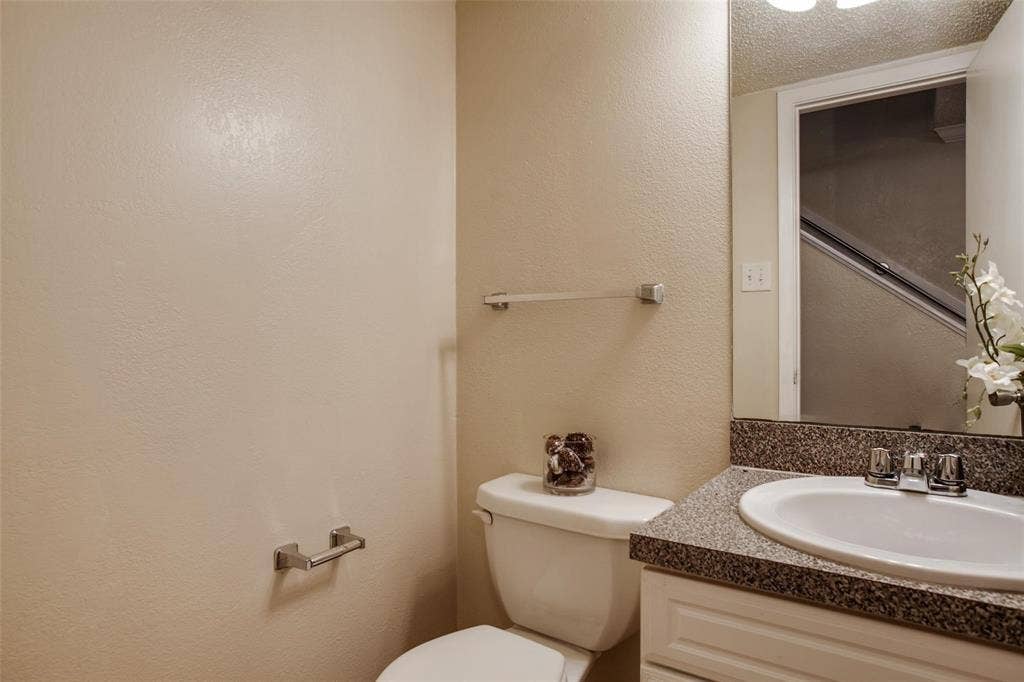 5322 Columbia Avenue, Dallas, TX 75214 A simple half bathroom with essential fixtures: a toilet and vanity with mirror.
