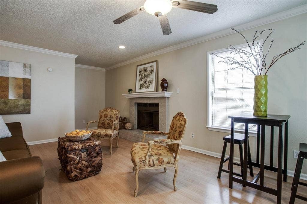 5322 Columbia Avenue, Dallas, TX 75214 Cozy living room featuring a warm fireplace, comfortable chairs and a central table, perfect for cozy moments.