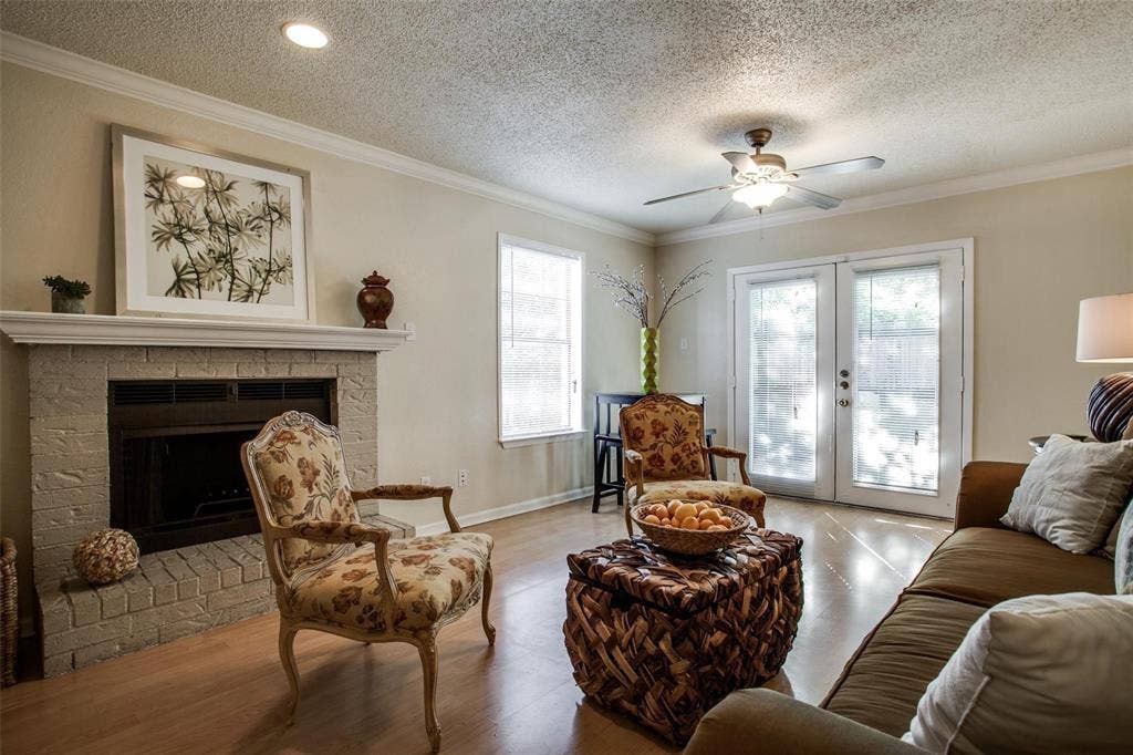 5322 Columbia Avenue, Dallas, TX 75214 Inviting living room scene with a ceiling fan, fireplace, soft couch and stylish chairs, perfect for gatherings and comfort.