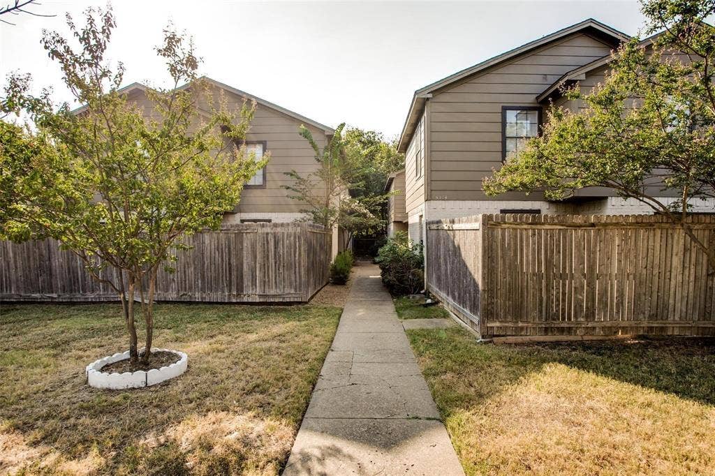 5322 Columbia Avenue, Dallas, TX 75214 A charming yard featuring a wooden fence surrounded by lush green trees, creating a peaceful outdoor space.