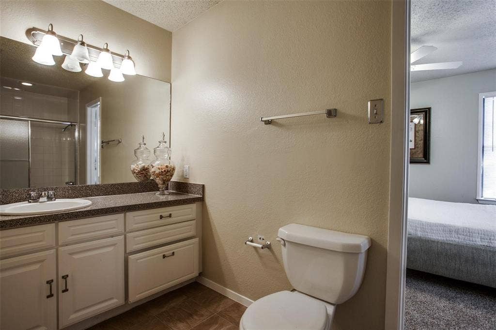 5322 Columbia Avenue, Dallas, TX 75214 A simple bathroom scene showcasing a toilet, sink, and mirror, creating a bright and inviting space for personal care.