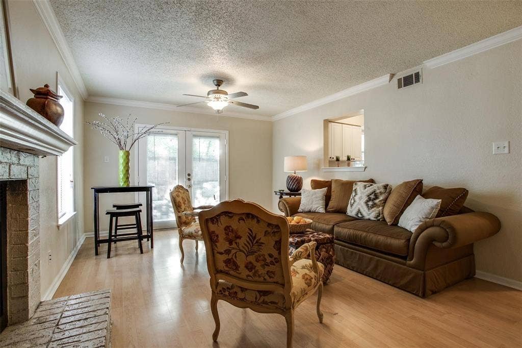 5322 Columbia Avenue, Dallas, TX 75214 Inviting living room scene with a fireplace, tall windows, soft couch and stylish chairs, perfect for gatherings and comfort.