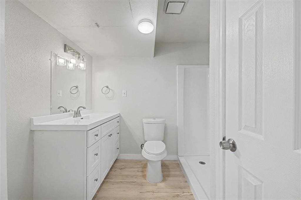 9021 White Settlement Road, #D, White Settlement, TX 76108 Bathroom featuring a single vanity with white cabinetry, a rectangular sink, and a light wood-finish floor