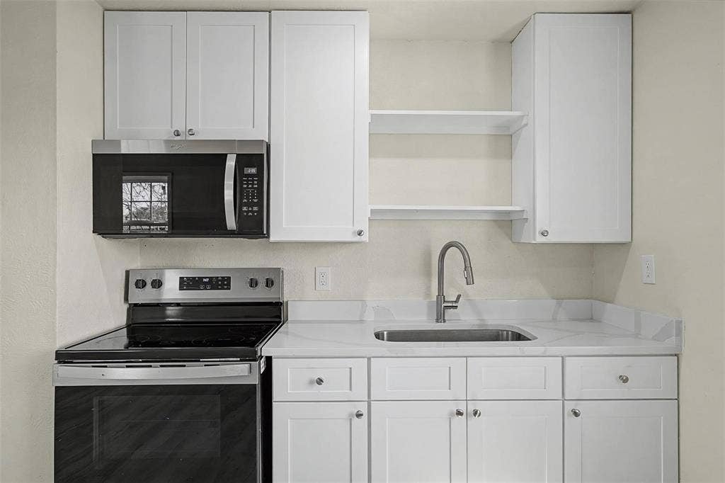 9021 White Settlement Road, #D, White Settlement, TX 76108 Kitchen featuring white shaker-style cabinetry, a stainless steel sink with a gooseneck faucet, white stone countertops, and a black over-the-range microwave