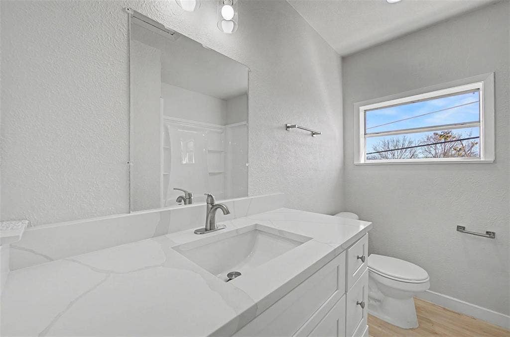 9021 White Settlement Road, #D, White Settlement, TX 76108 Bathroom featuring a white vanity with a built-in sink and light-colored countertop, brushed nickel faucet, large wall-mounted mirror, and a horizontal window