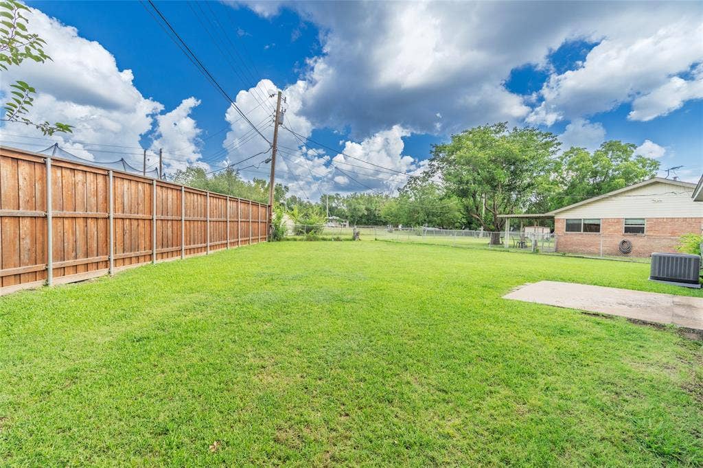 3407 Highmeadow Lane, Greenville, TX 75402 Expansive backyard featuring a manicured lawn, full wood privacy fencing, and a concrete patio pad