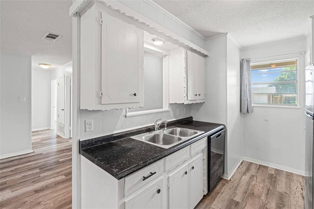 3407 Highmeadow Lane, Greenville, TX 75402 Kitchen featuring white cabinetry, dark countertops, a double-basin stainless steel sink, and wood-finish flooring