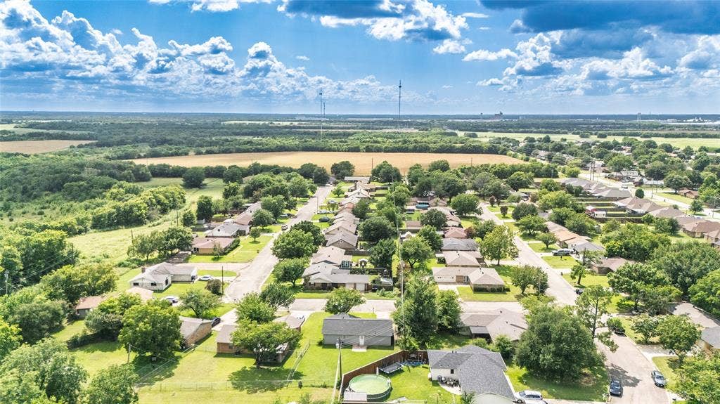 3407 Highmeadow Lane, Greenville, TX 75402 Residential neighborhood featuring single-story homes with dark shingle roofs, mature trees, paved streets, and expansive green spaces