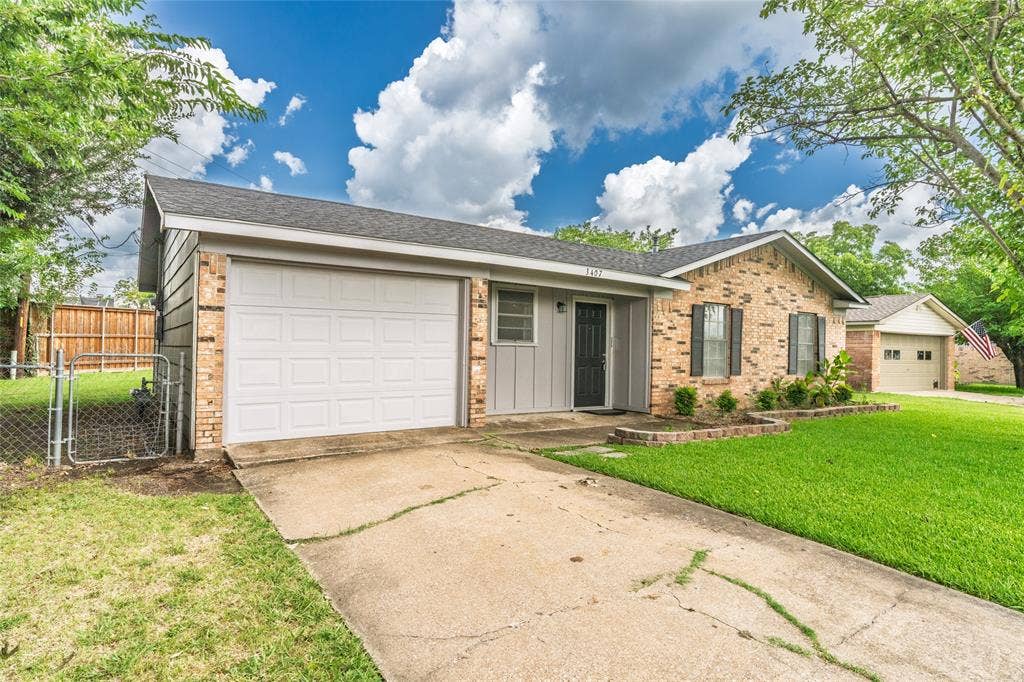 3407 Highmeadow Lane, Greenville, TX 75402 Brick and siding exterior with an attached garage, a paved driveway, and a chain-link fence