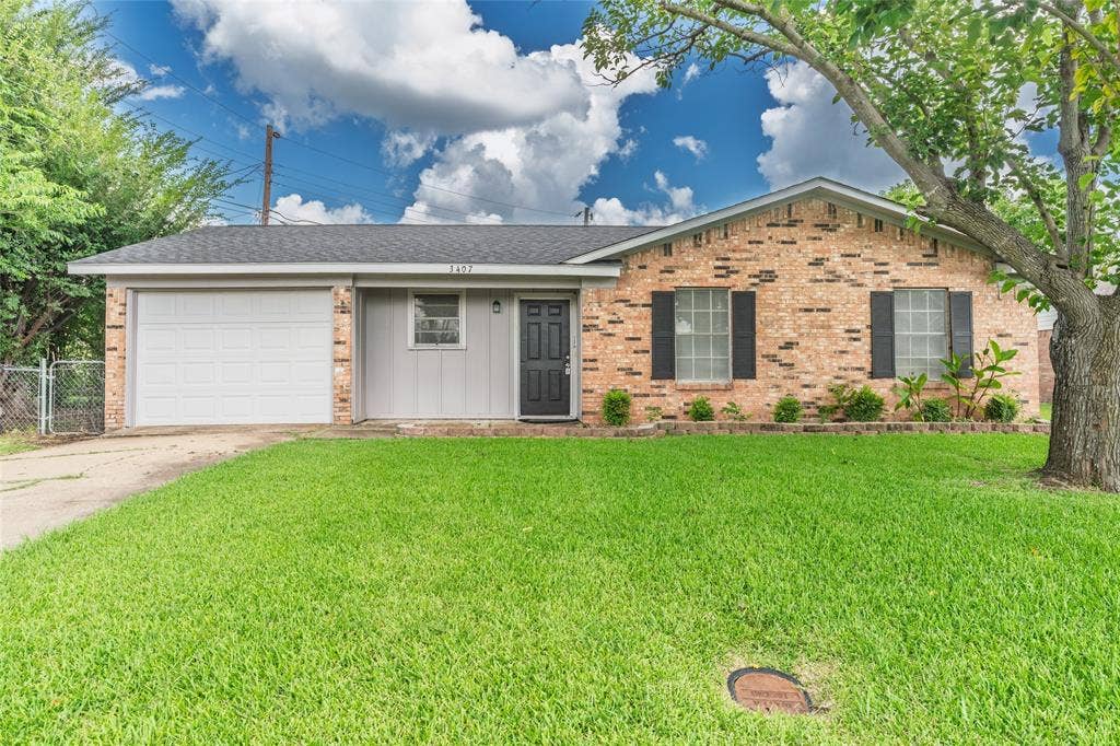 3407 Highmeadow Lane, Greenville, TX 75402 Brick and siding exterior featuring a single-car garage, mature front yard tree, and an established lawn