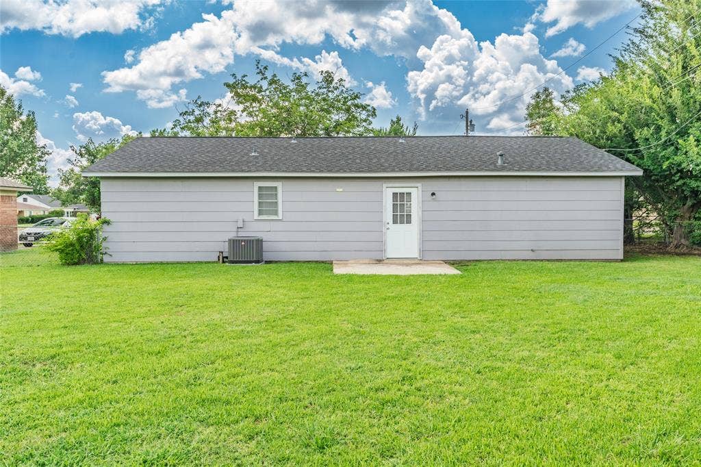 3407 Highmeadow Lane, Greenville, TX 75402 Expansive green lawn with a gray exterior, white entry door, and a single-pane window