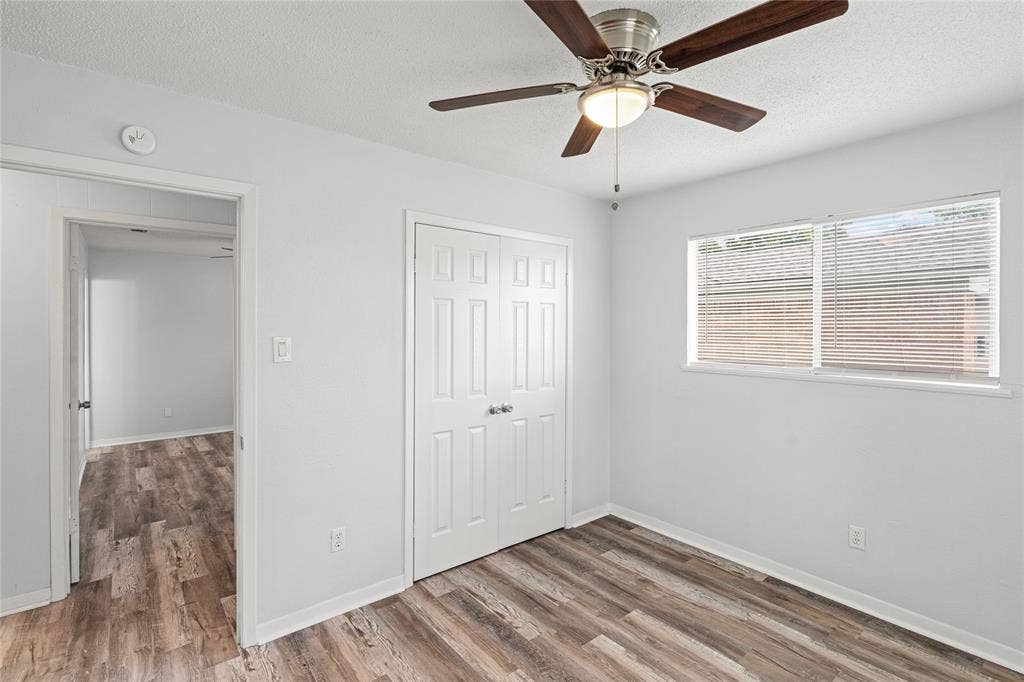 3407 Highmeadow Lane, Greenville, TX 75402 Room featuring wood-finish flooring, a ceiling fan with integrated lighting, a double-door closet, and a window with horizontal blinds