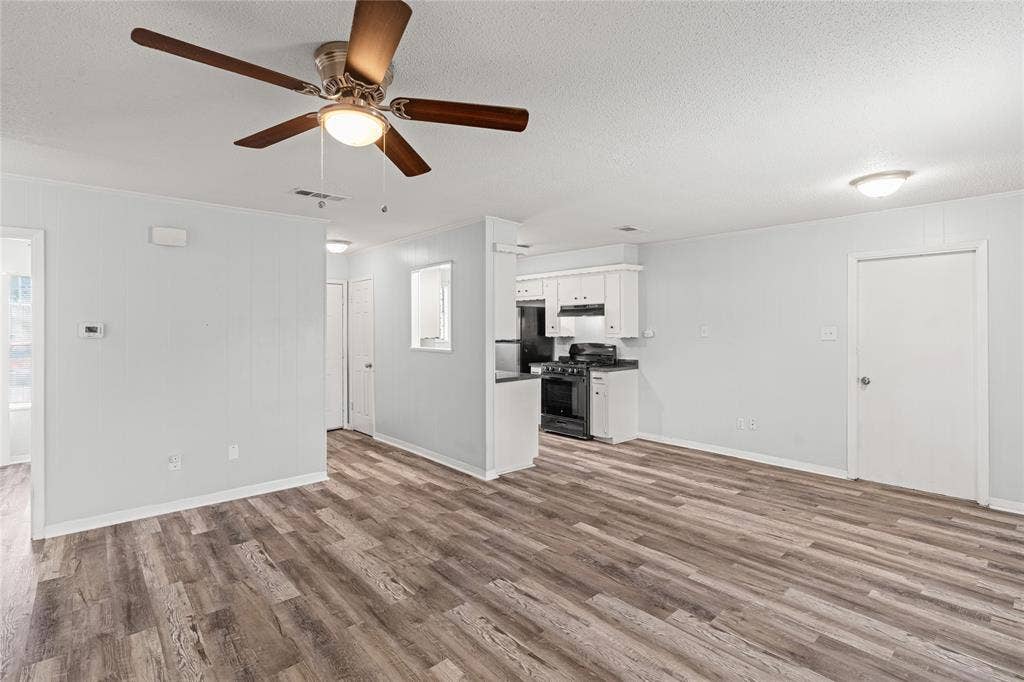 3407 Highmeadow Lane, Greenville, TX 75402 Spacious room featuring wood-finish flooring, light gray walls, and a ceiling fan with integrated lighting