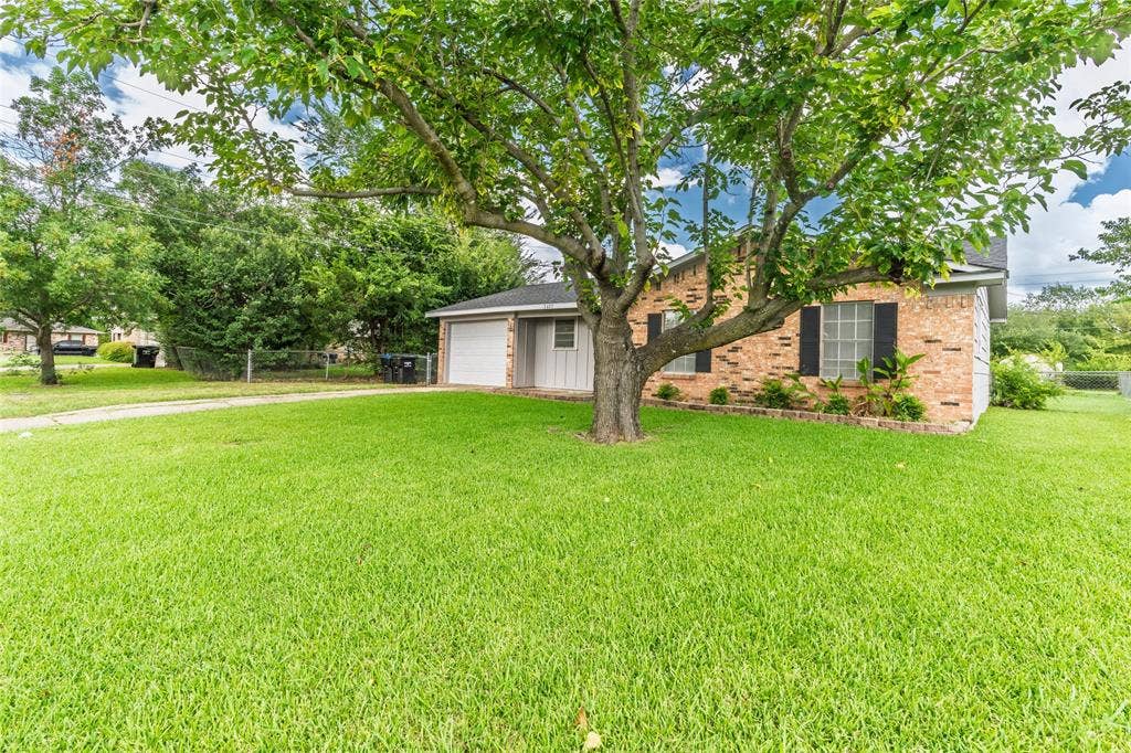 3407 Highmeadow Lane, Greenville, TX 75402 Expansive front yard with a mature shade tree, a brick exterior, and a single-car garage