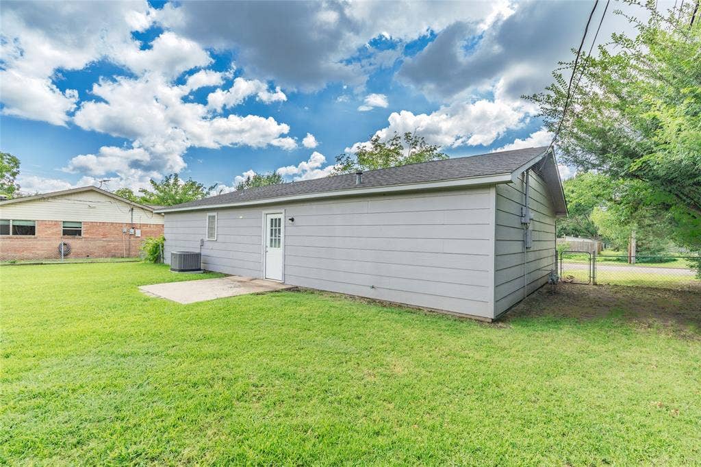 3407 Highmeadow Lane, Greenville, TX 75402 Expansive green lawn with a detached building featuring horizontal siding and a side entry door