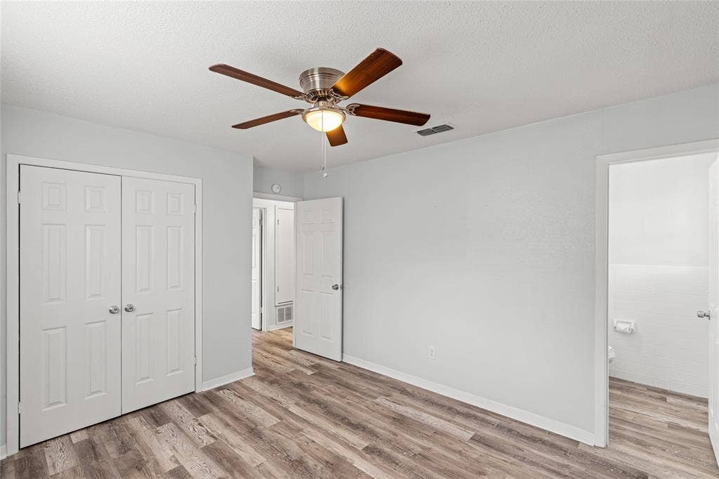 3407 Highmeadow Lane, Greenville, TX 75402 Spacious room featuring wood-finish flooring, a ceiling fan with light fixture, and white bi-fold closet doors