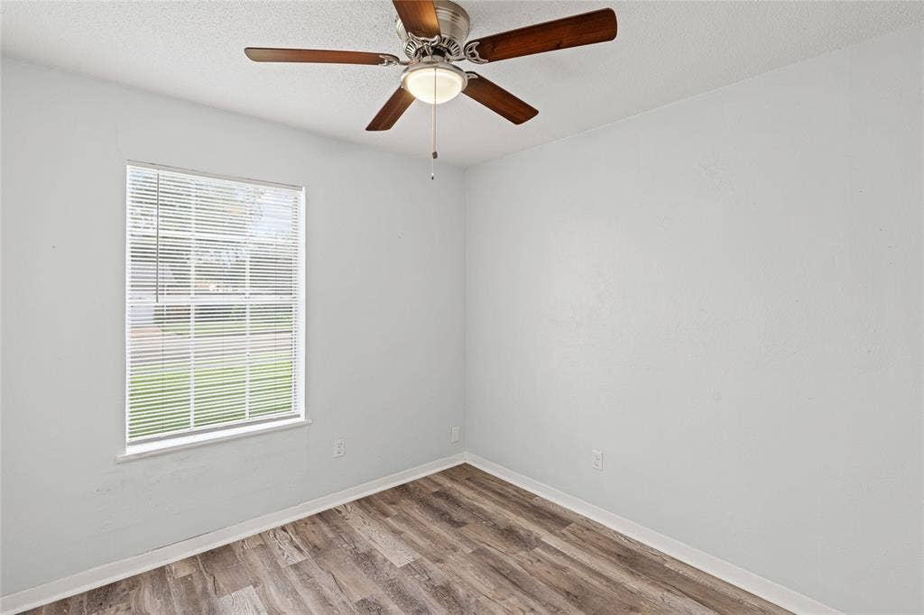 3407 Highmeadow Lane, Greenville, TX 75402 Room featuring wood-finish flooring, a ceiling fan with integrated lighting, and a window with blinds
