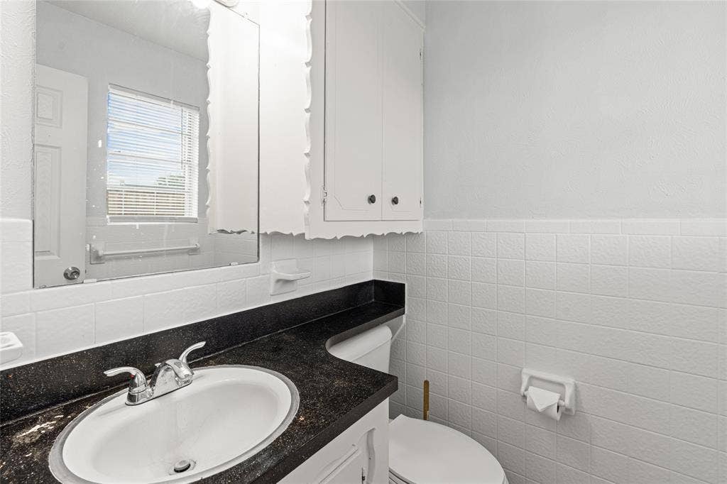 3407 Highmeadow Lane, Greenville, TX 75402 Bathroom featuring a vanity with an integrated sink, dark countertop, and chrome faucet