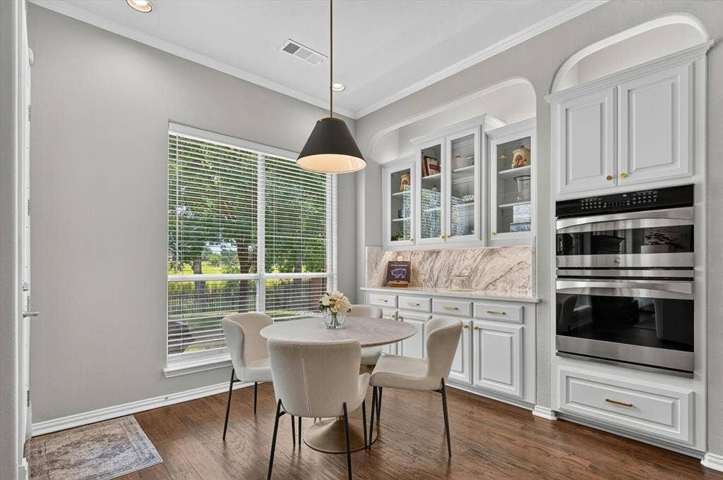 8405 Gallery Way, McKinney, TX 75072 Integrated kitchen cabinetry featuring built-in double ovens, a marble-patterned backsplash, and glass-front upper cabinets