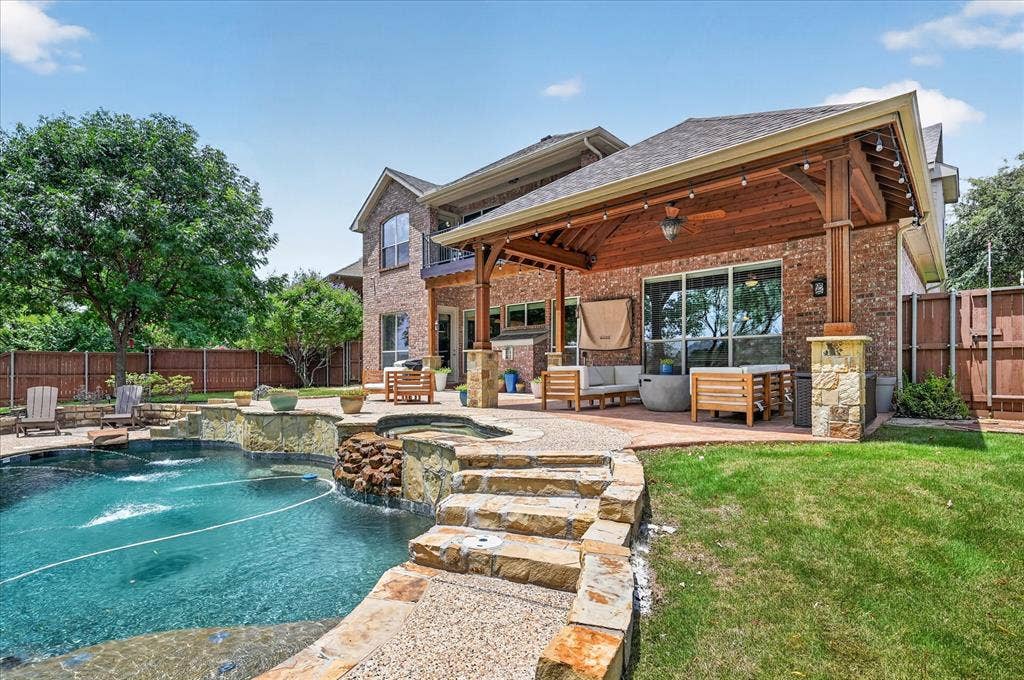 8405 Gallery Way, McKinney, TX 75072 Expansive backyard featuring a custom pool with stone detailing, a built-in spa with a waterfall feature, and a covered patio with a wood-finish ceiling and exposed beams