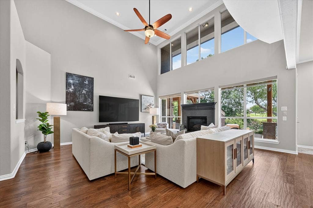 8405 Gallery Way, McKinney, TX 75072 Vaulted ceiling great room featuring wood-finish flooring, a fireplace with a dark wood mantel, and expansive windows