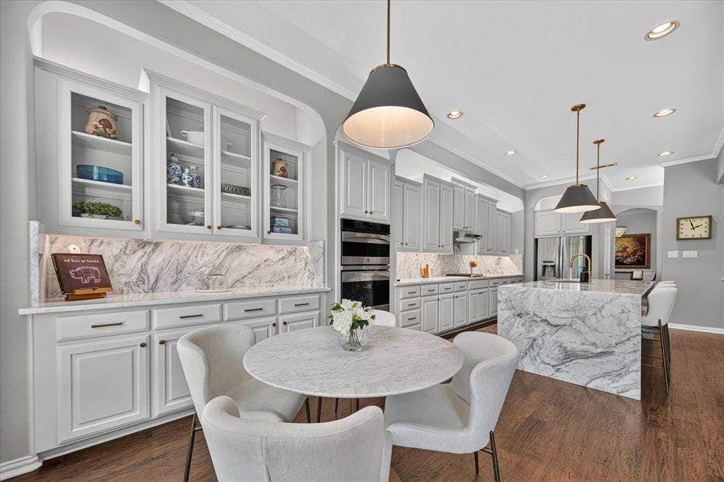 8405 Gallery Way, McKinney, TX 75072 Gourmet kitchen featuring a waterfall island, integrated double ovens, and extensive cabinetry with glass-front uppers
