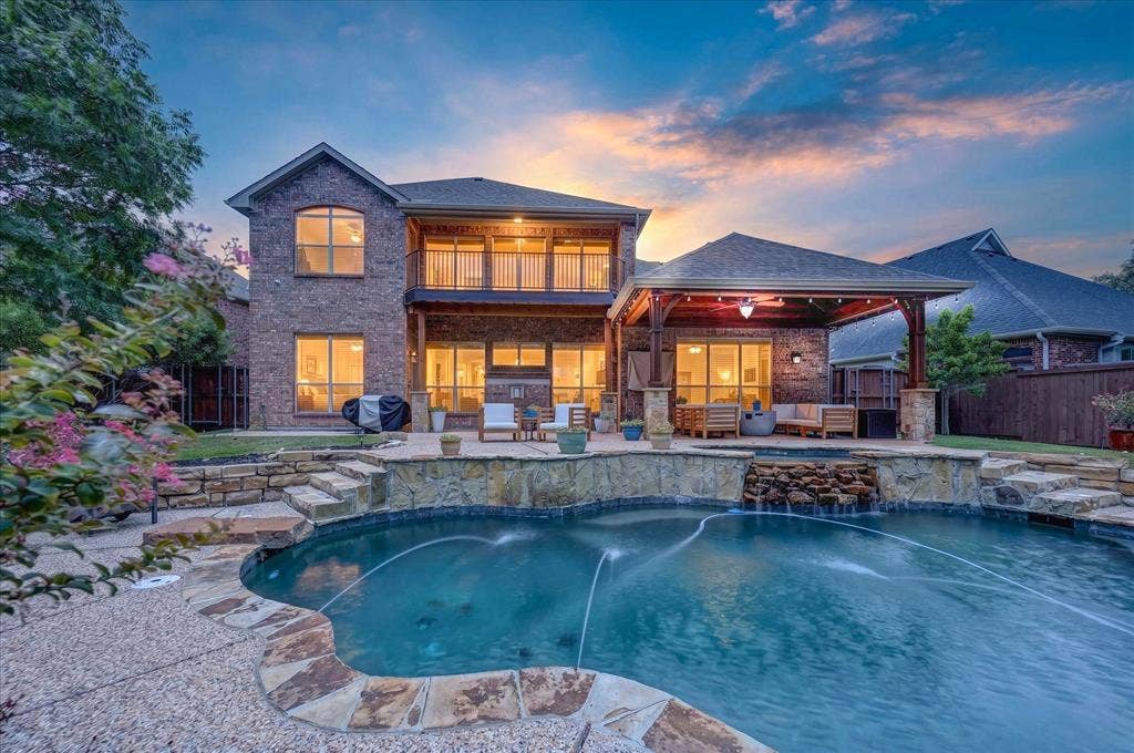 8405 Gallery Way, McKinney, TX 75072 Backyard oasis featuring a custom-shaped swimming pool with stone coping and a waterfall feature