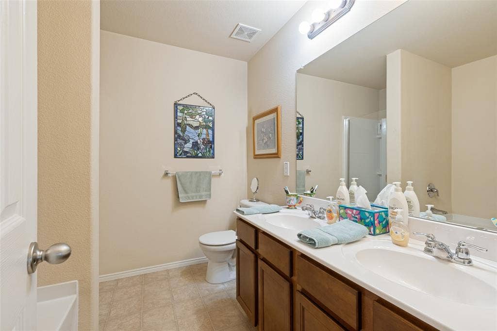 317 Amethyst Drive, Fort Worth, TX 76131 Bathroom featuring a dual vanity with integrated sinks, wood-finish cabinetry, and a large wall-mounted mirror