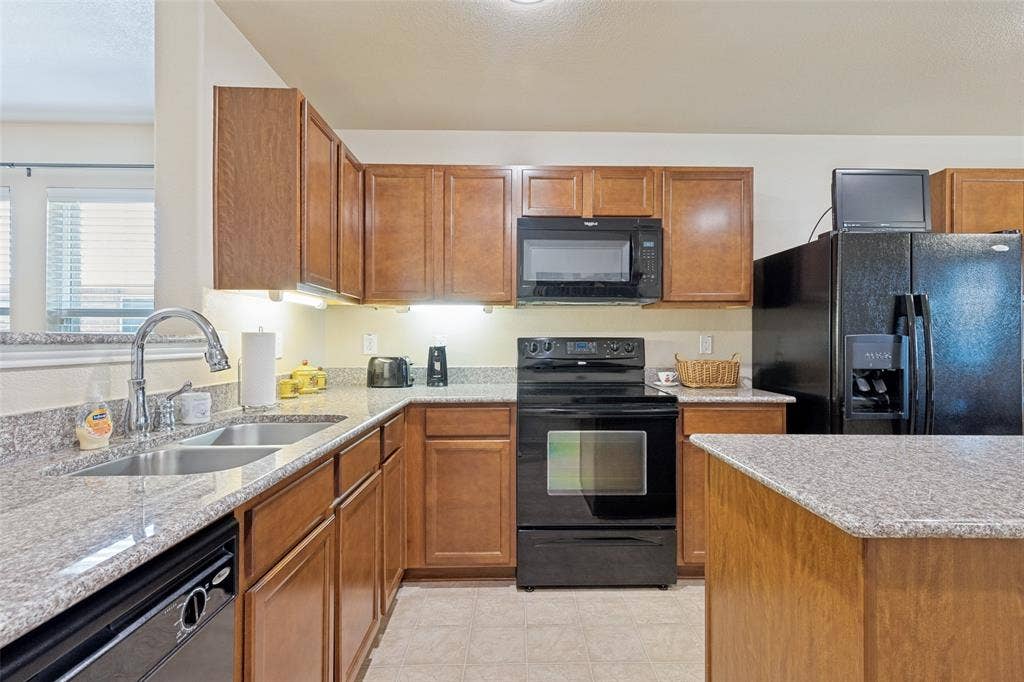317 Amethyst Drive, Fort Worth, TX 76131 Kitchen featuring granite countertops, wood cabinetry, dual basin stainless steel sink, black electric range, and black built-in microwave