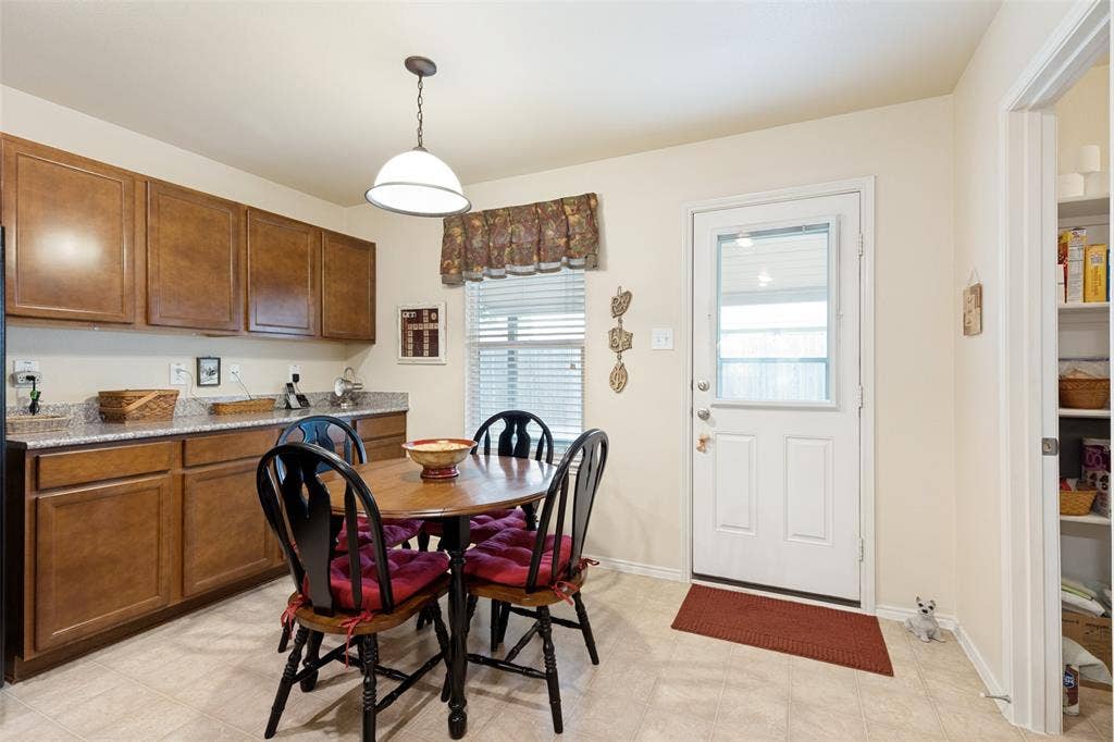 317 Amethyst Drive, Fort Worth, TX 76131 Kitchen area featuring wood-finish cabinetry, light-toned countertops, and a white exterior door with an upper glass pane