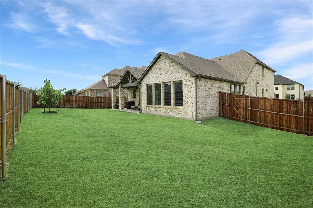 919 Edgehurst Drive, Princeton, TX 75071 Expansive green lawn with a young tree, bordered by a privacy fence