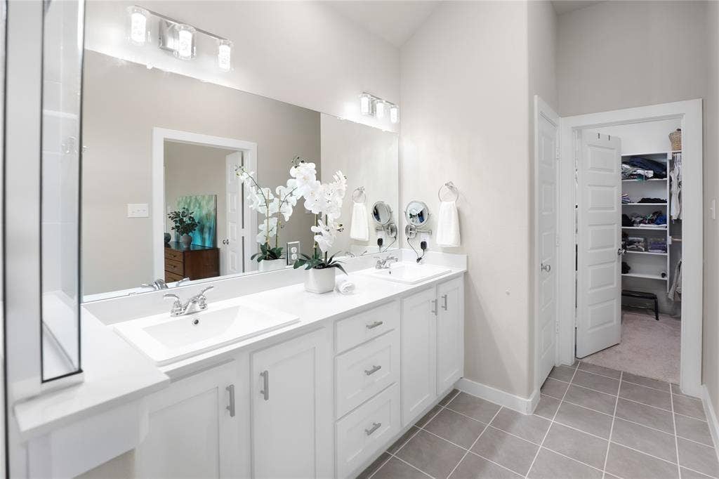 919 Edgehurst Drive, Princeton, TX 75071 Dual vanity with white cabinetry and integrated sinks, complemented by a large mirror and overhead lighting