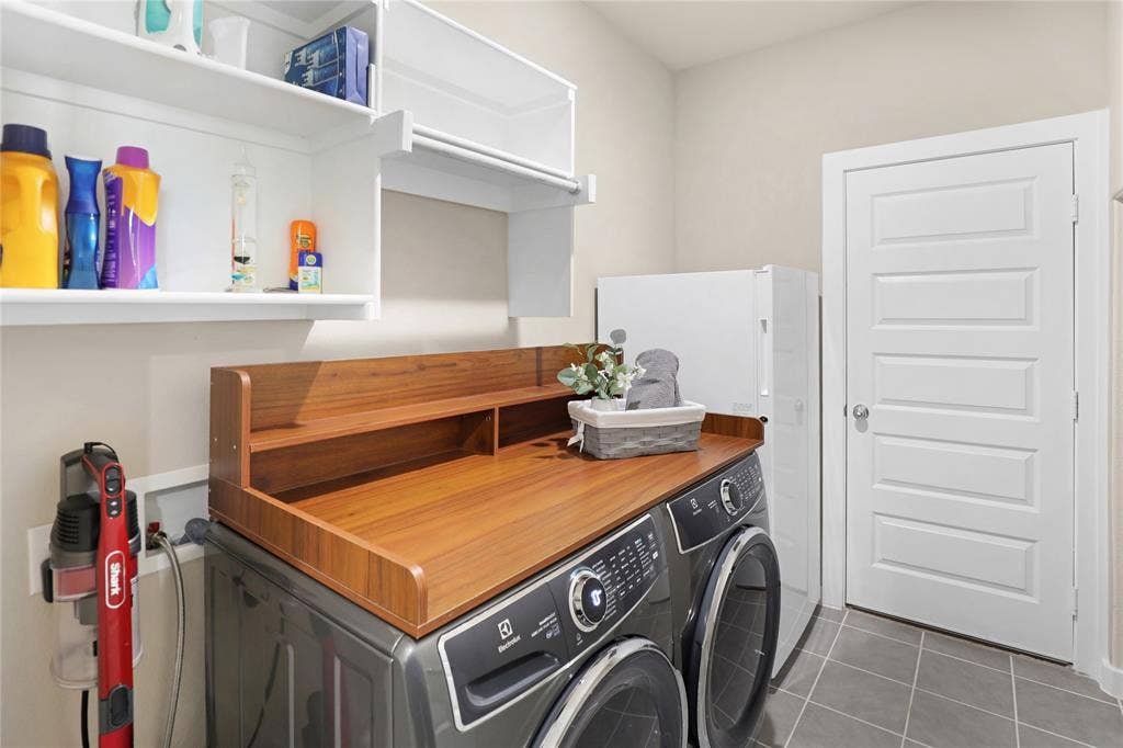919 Edgehurst Drive, Princeton, TX 75071 Dedicated laundry area featuring a wood-finish countertop, integrated shelving, and white overhead cabinetry