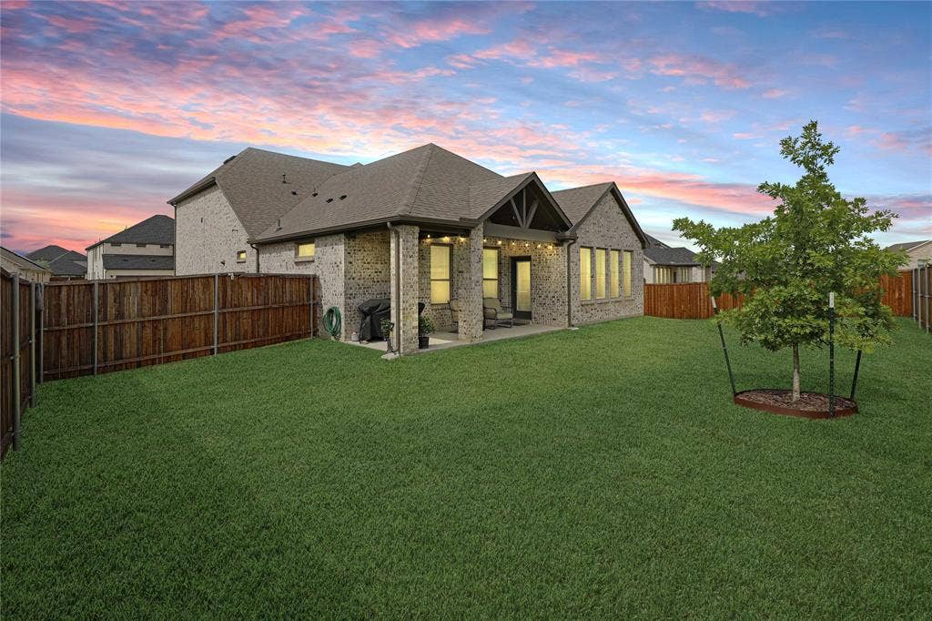 919 Edgehurst Drive, Princeton, TX 75071 Expansive backyard featuring a manicured lawn, a young tree with a tree ring, and wood fencing