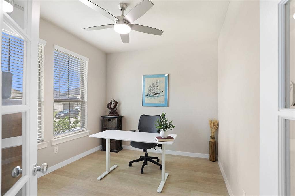919 Edgehurst Drive, Princeton, TX 75071 Versatile room featuring two large windows with blinds, light wood-finish flooring, and a ceiling fan with integrated lighting