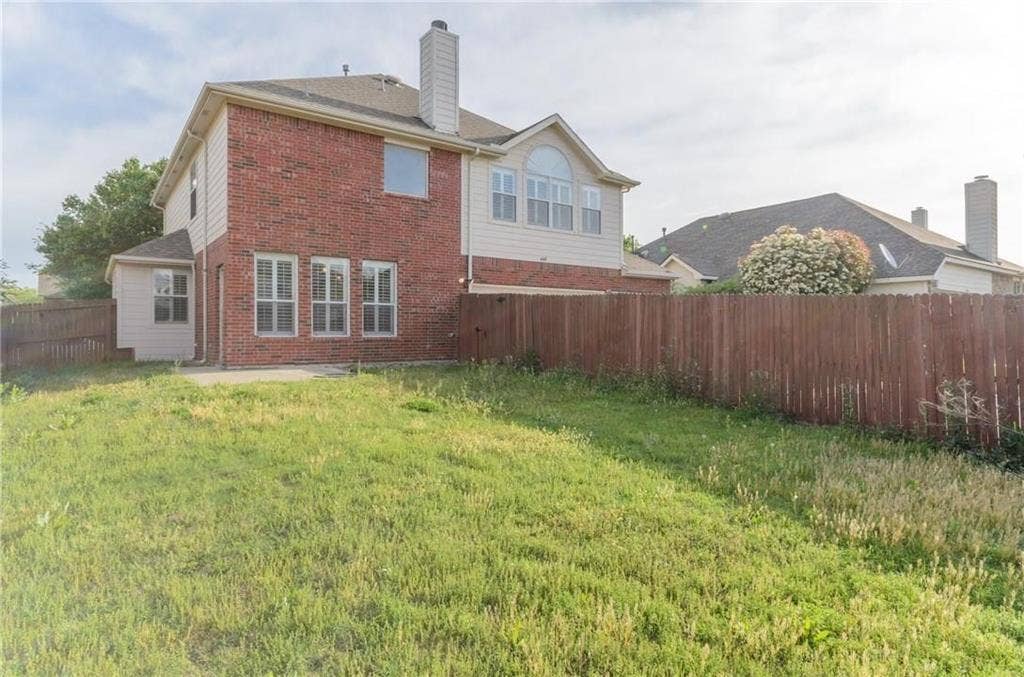 4440 Waskom Drive, Plano, TX 75024 Expansive backyard featuring a privacy fence, concrete patio, and a two-story exterior with brick and siding finishes